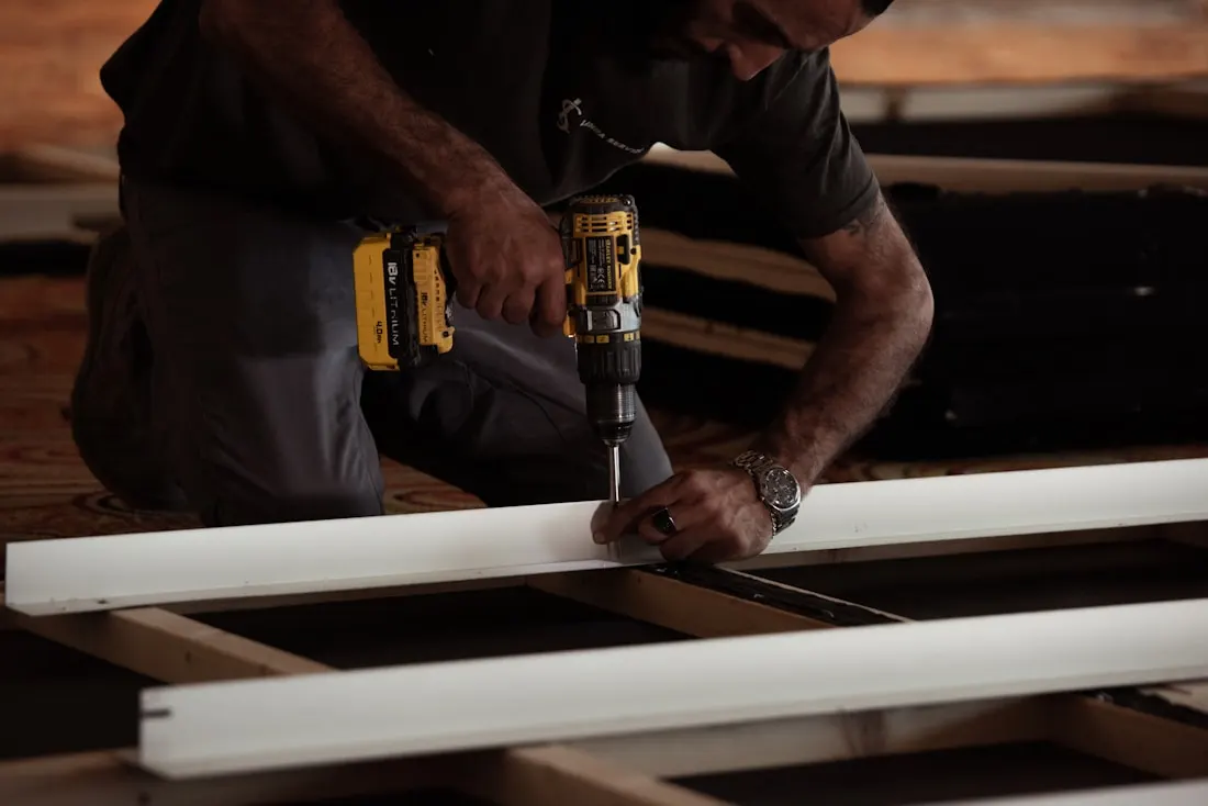 Hands driving a screw into a board with a cordless drill