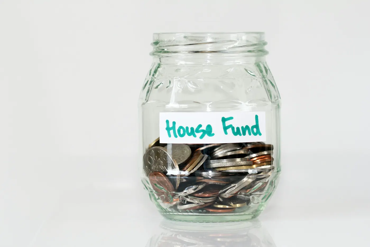 A glass jar of coins labeled “House Fund”